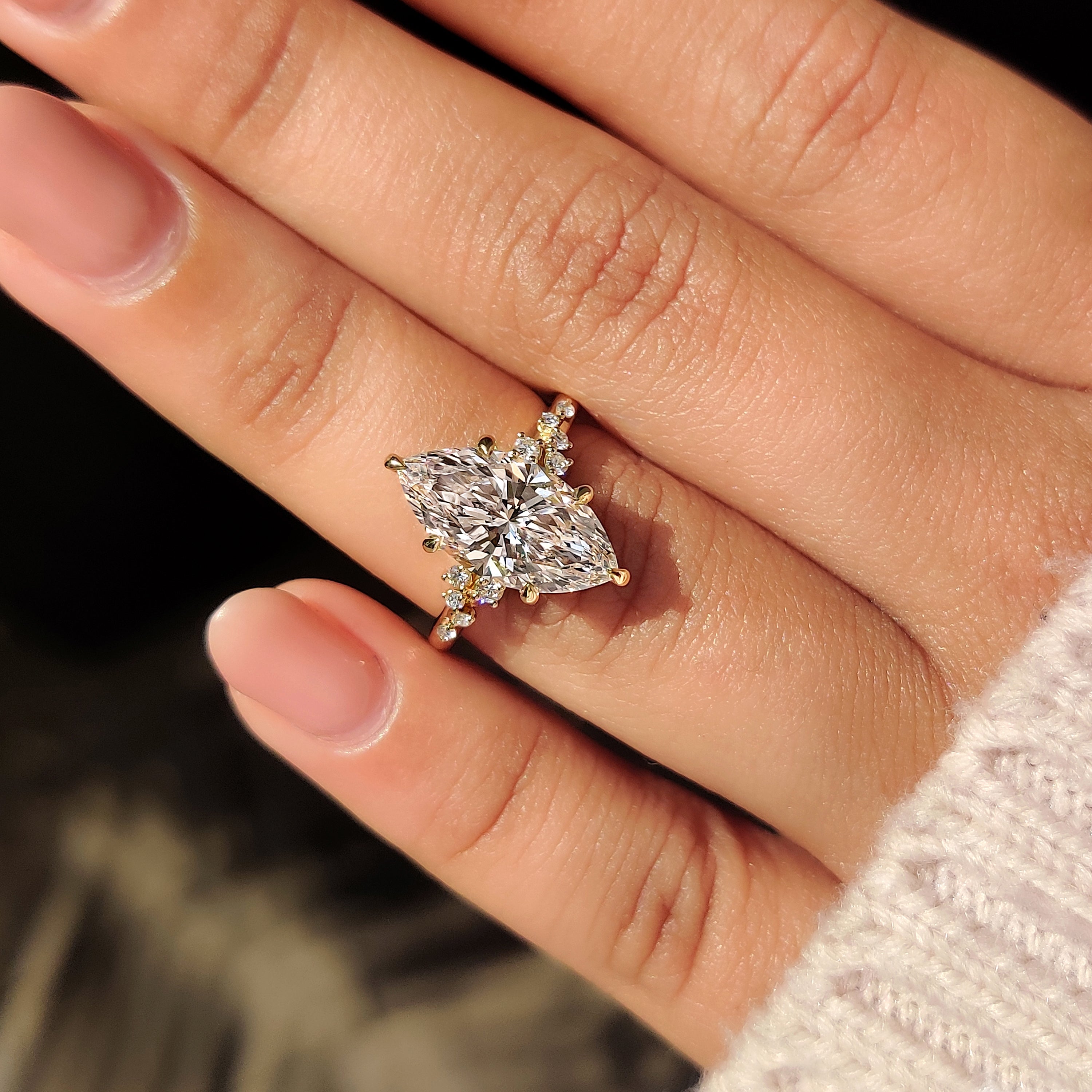 Cluster design highlights marquise cut engagement ring with side stones.
