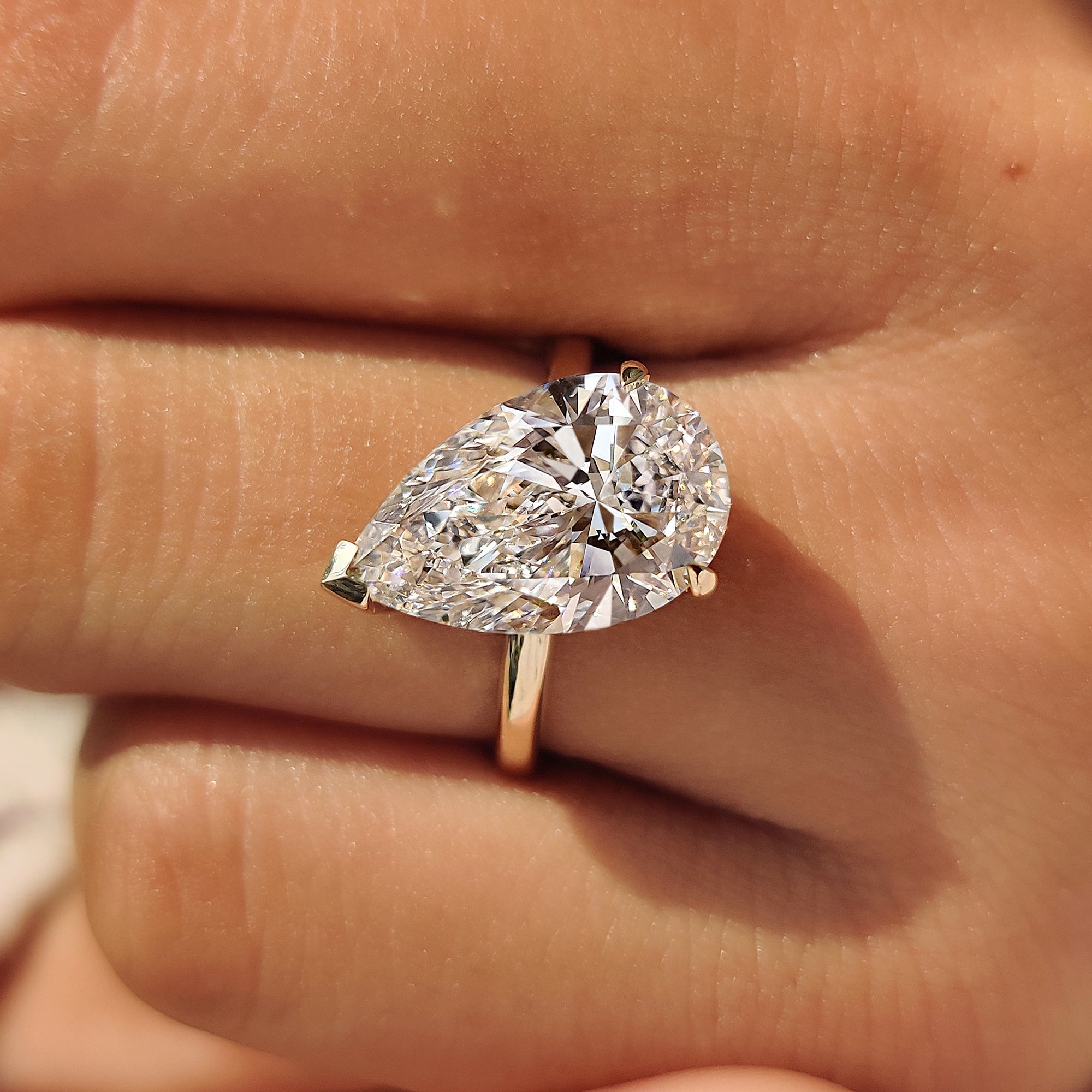 Close-up of the V and two claw prong setting on a pear diamond ring.
