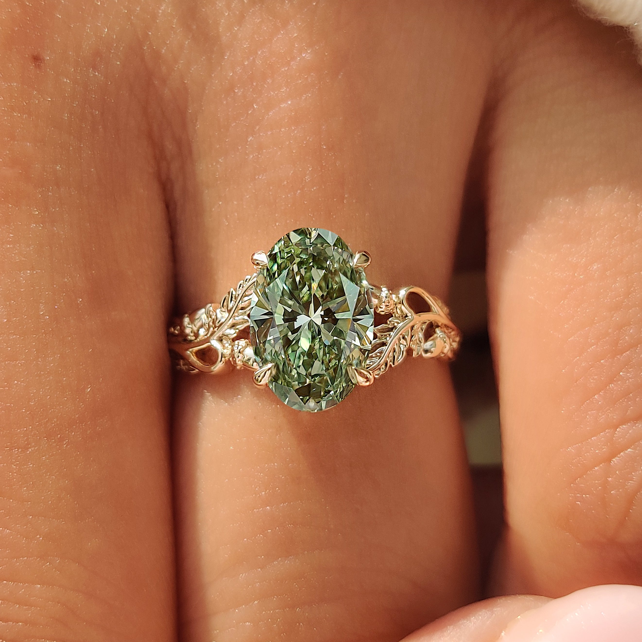 Green oval center diamond held by four claw prongs.
