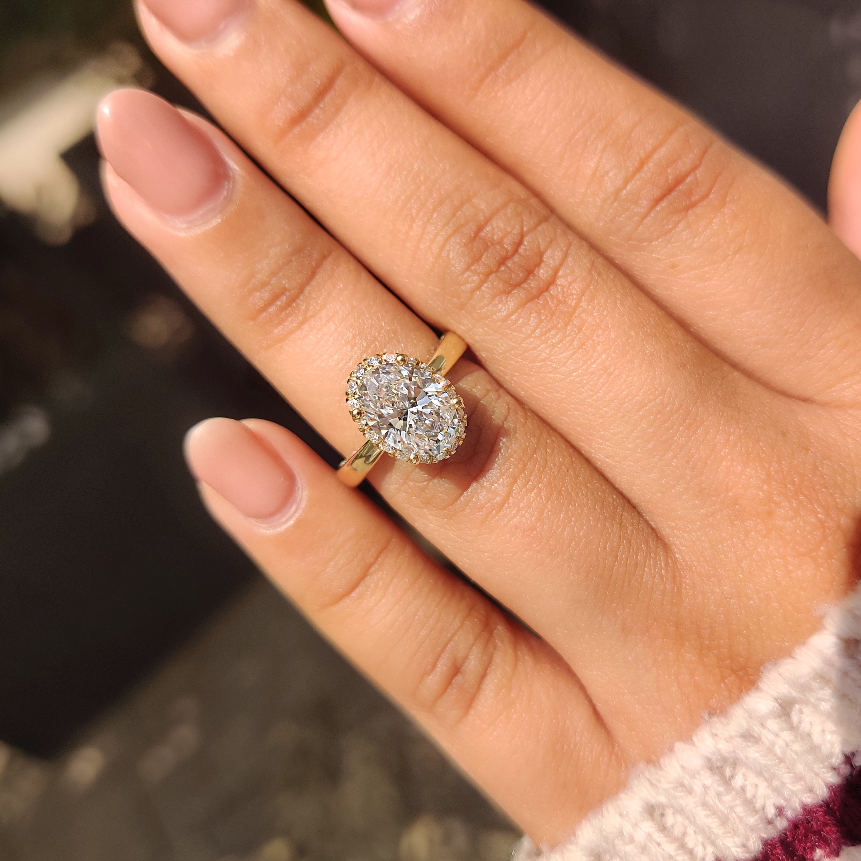 Halo setting surrounds oval diamond ring with added brilliance.
