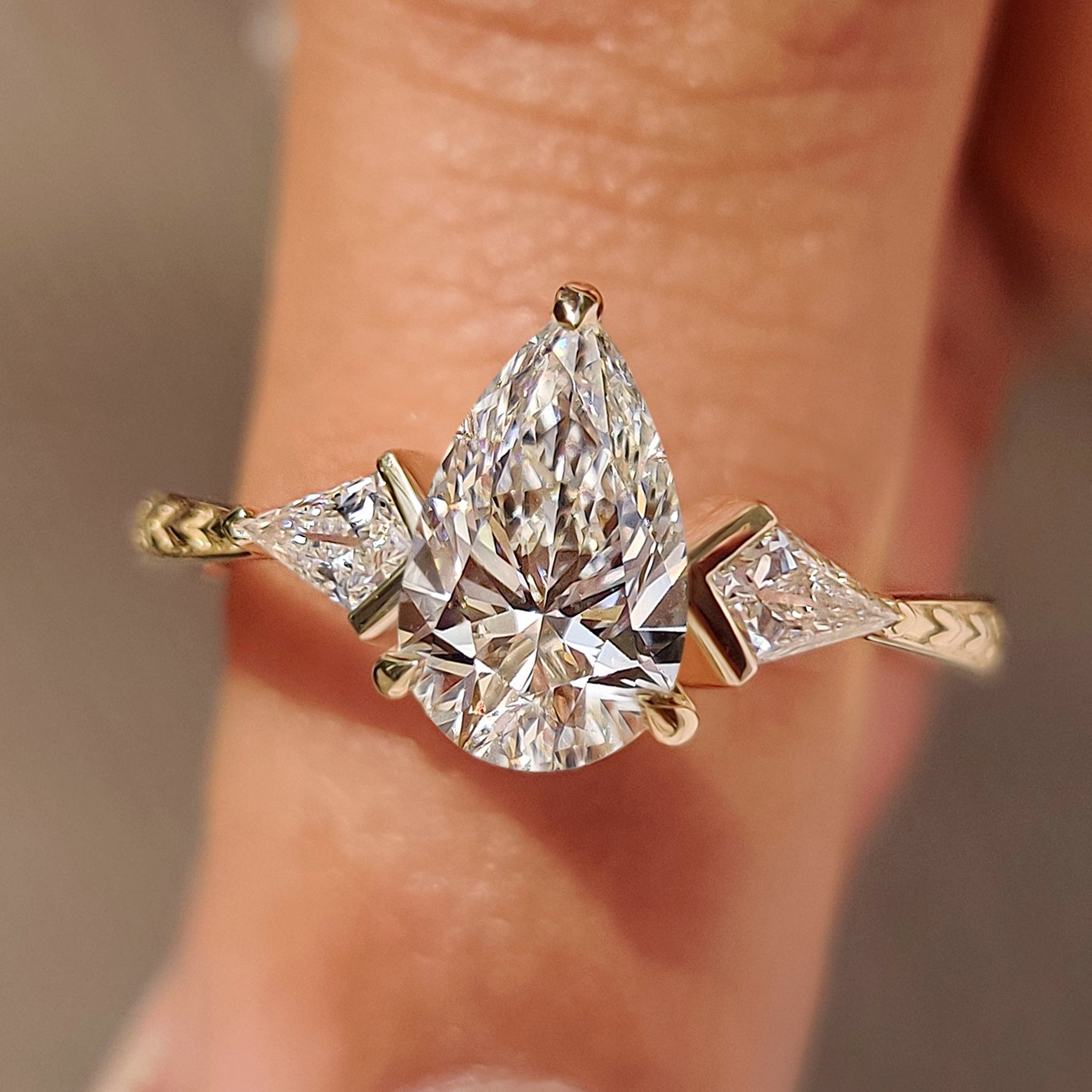Three diamond ring with pear center and kite sides.
