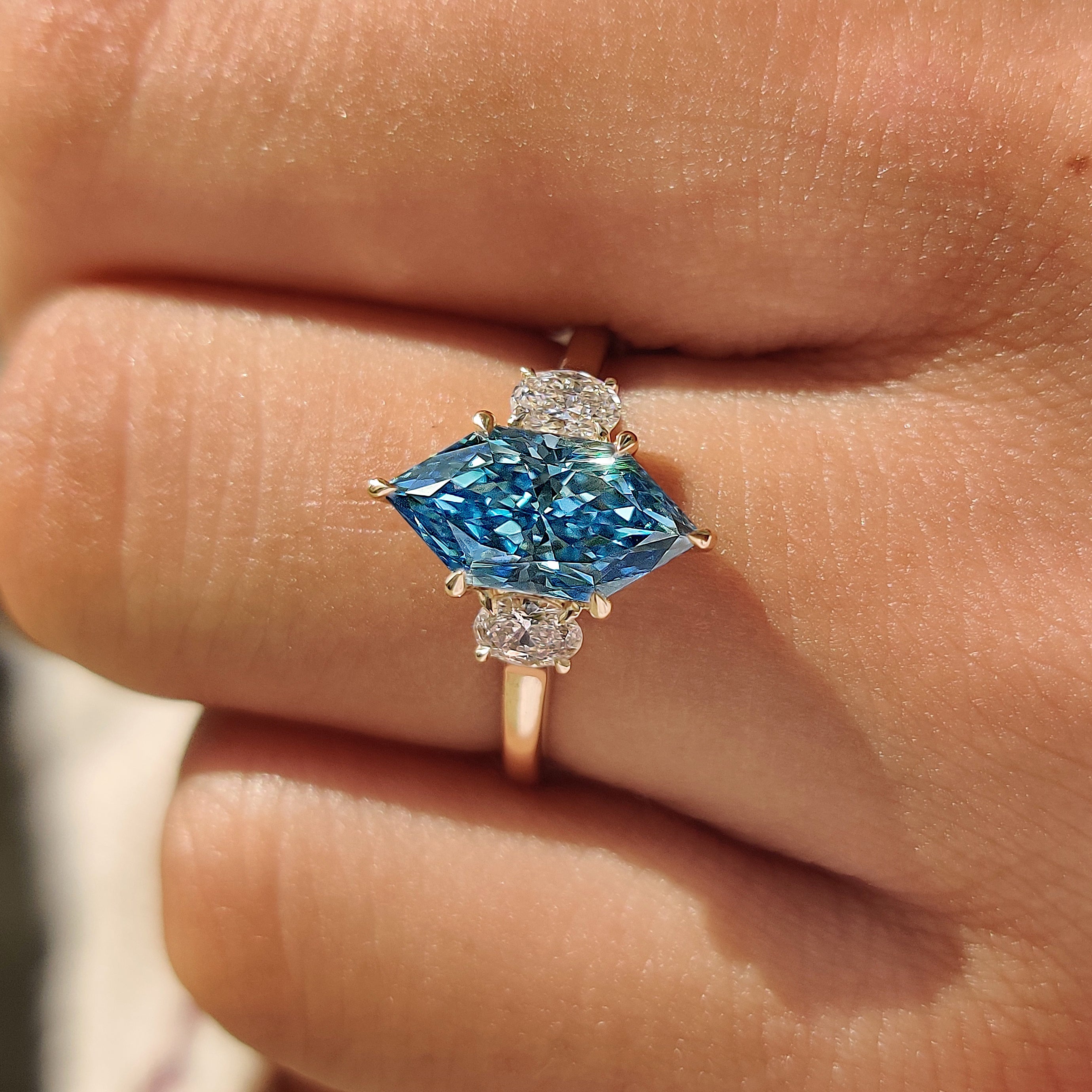 Basket setting trilogy ring with prong set oval side stones.
