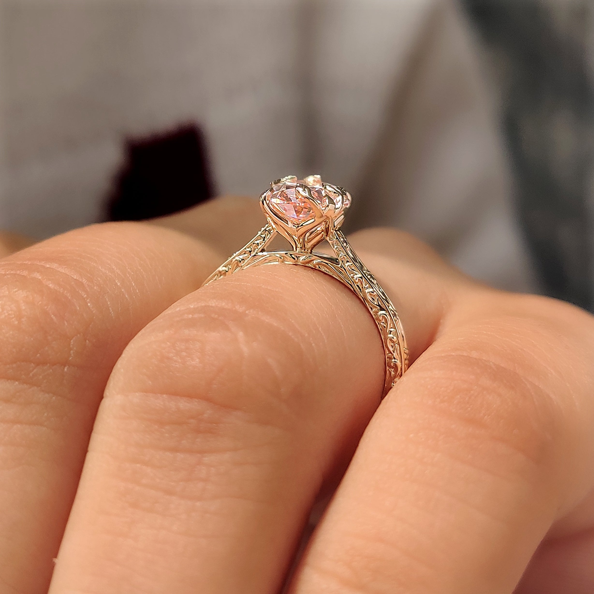 Pink oval engagement ring with hand engraved filigree design.
