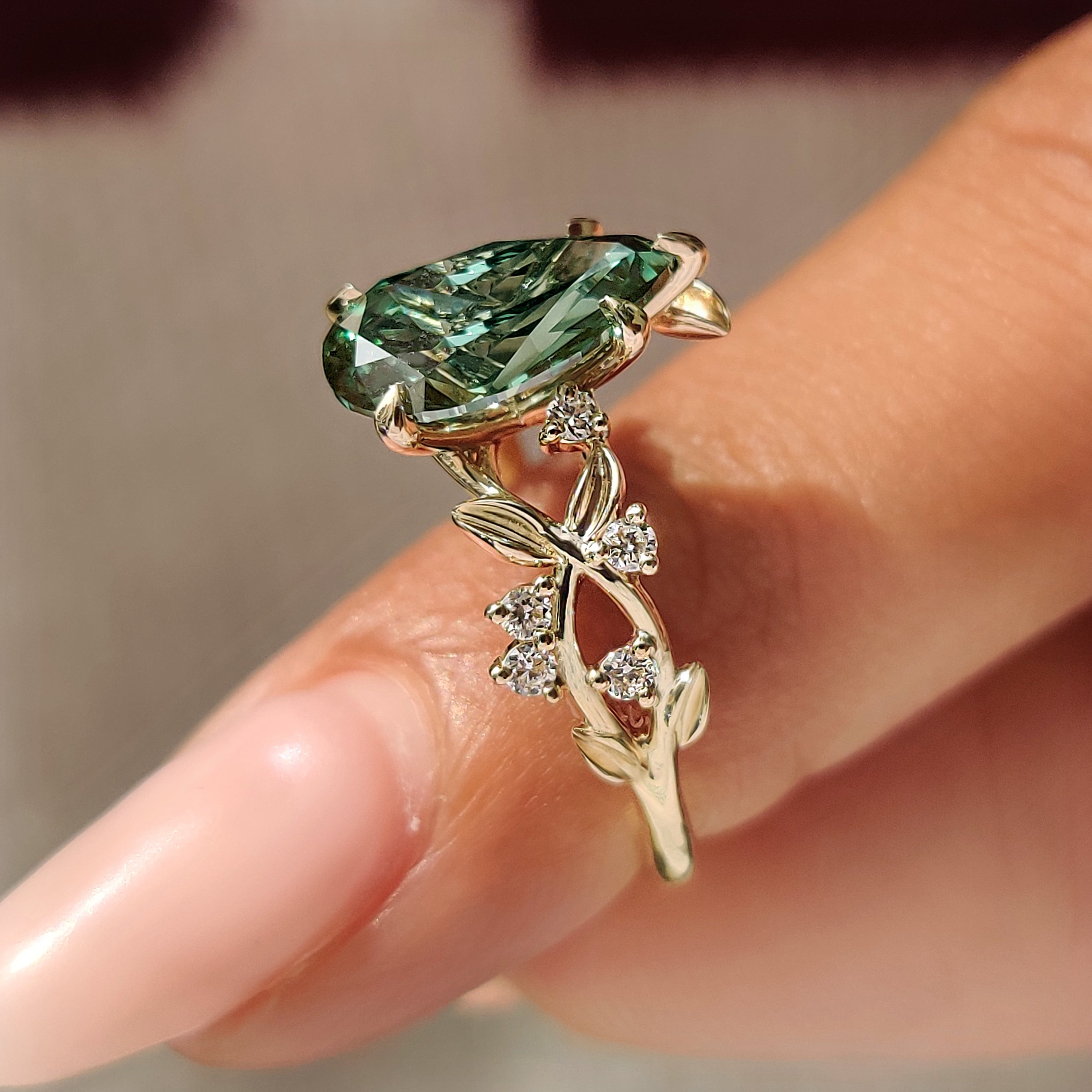 Green pear shaped diamond with five claw prong setting.
