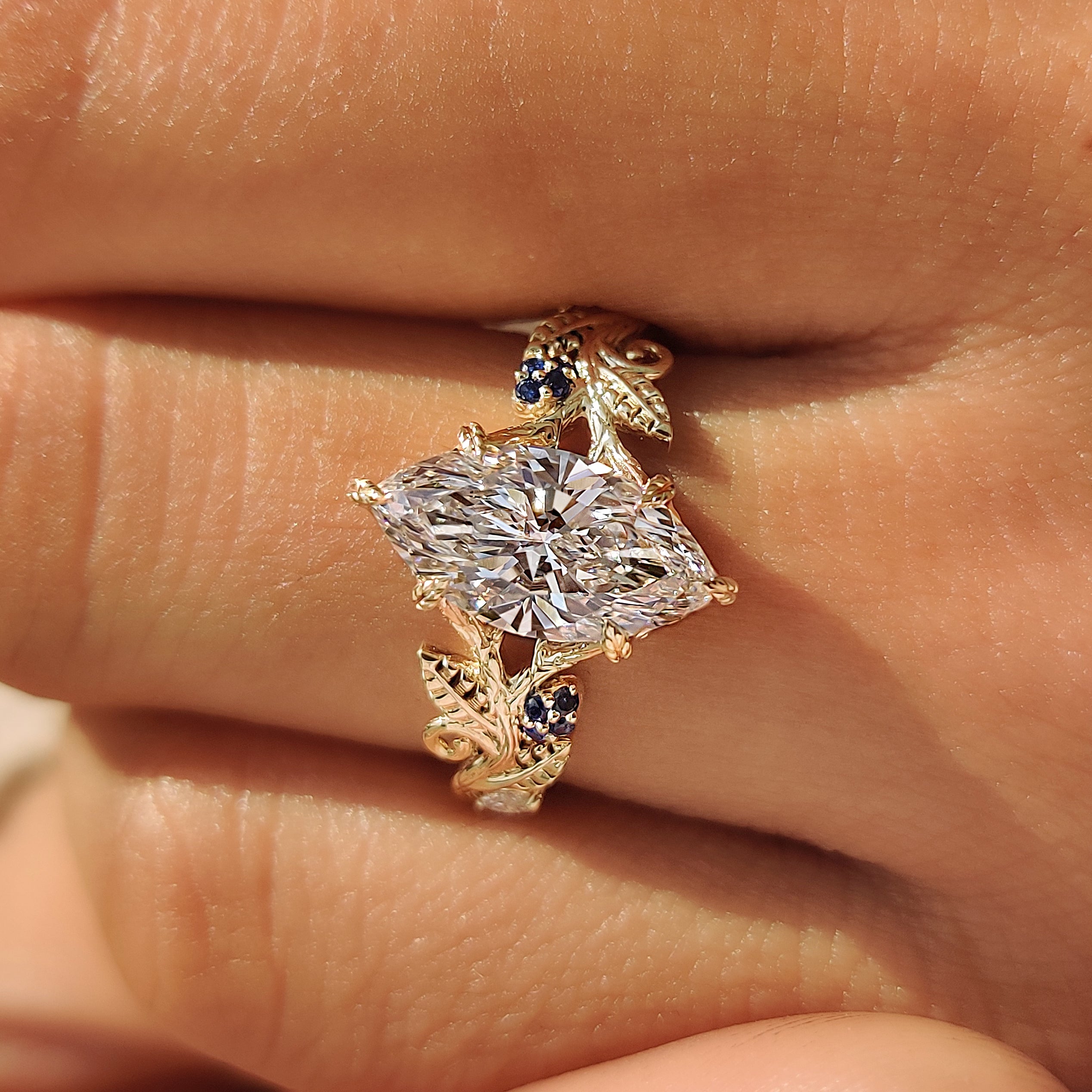 Lab grown marquise diamond ring with round blue sapphires.
