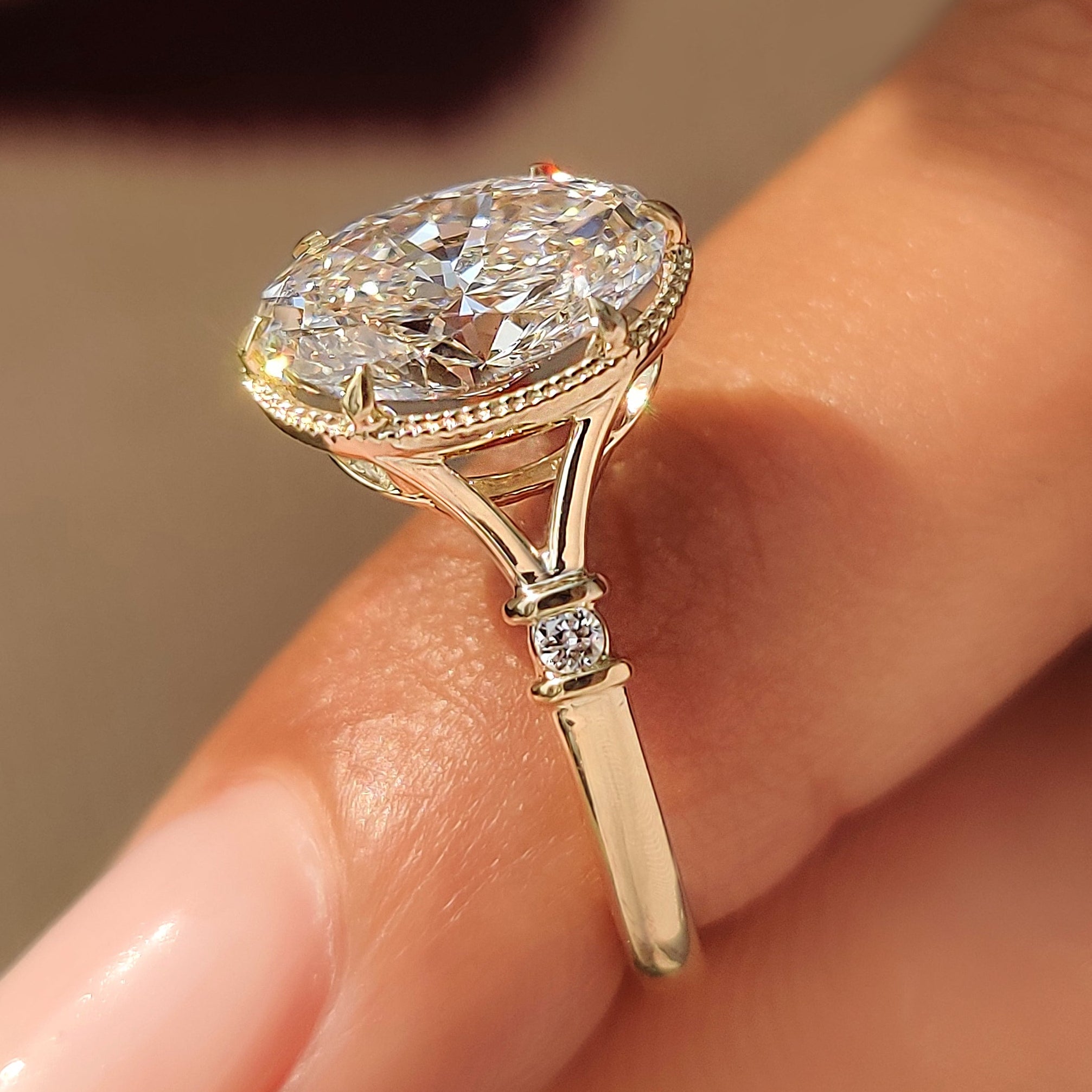 Six claw prong setting secures an oval cut center diamond.
