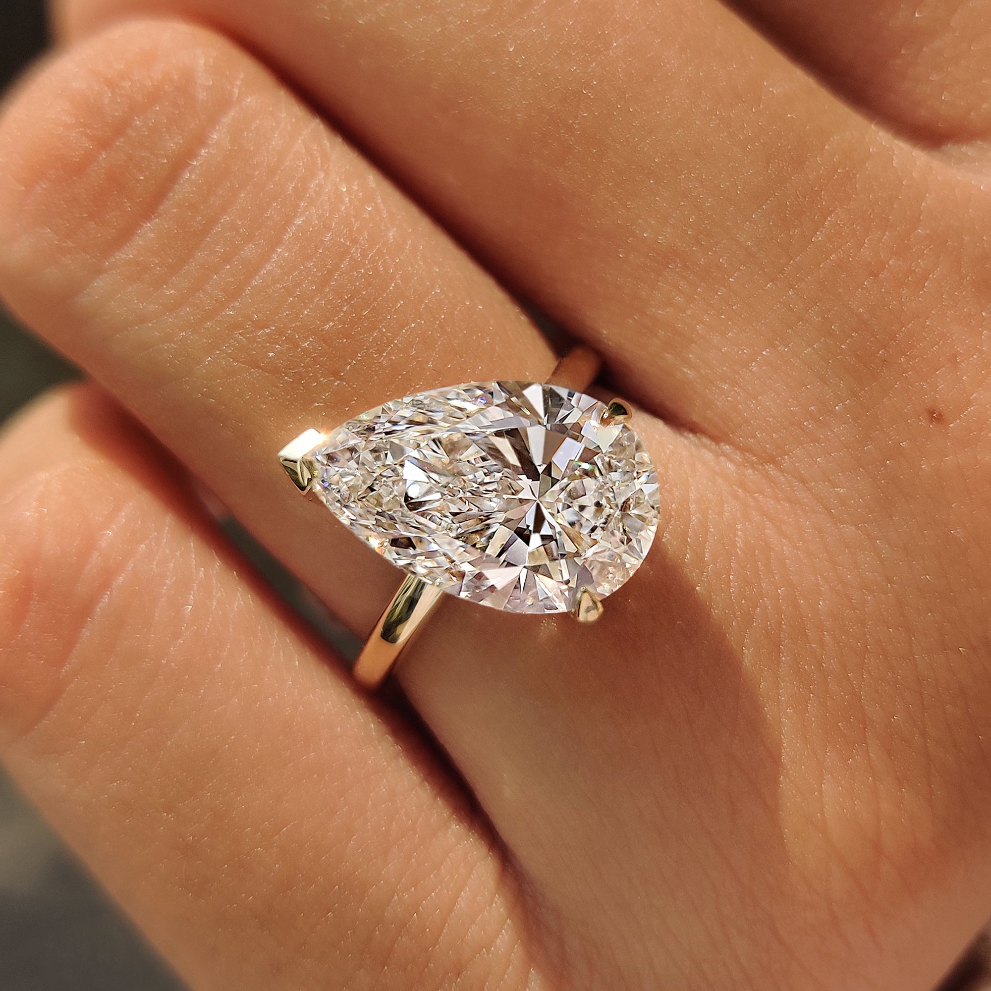Pear cut solitaire engagement ring with a yellow gold band.

