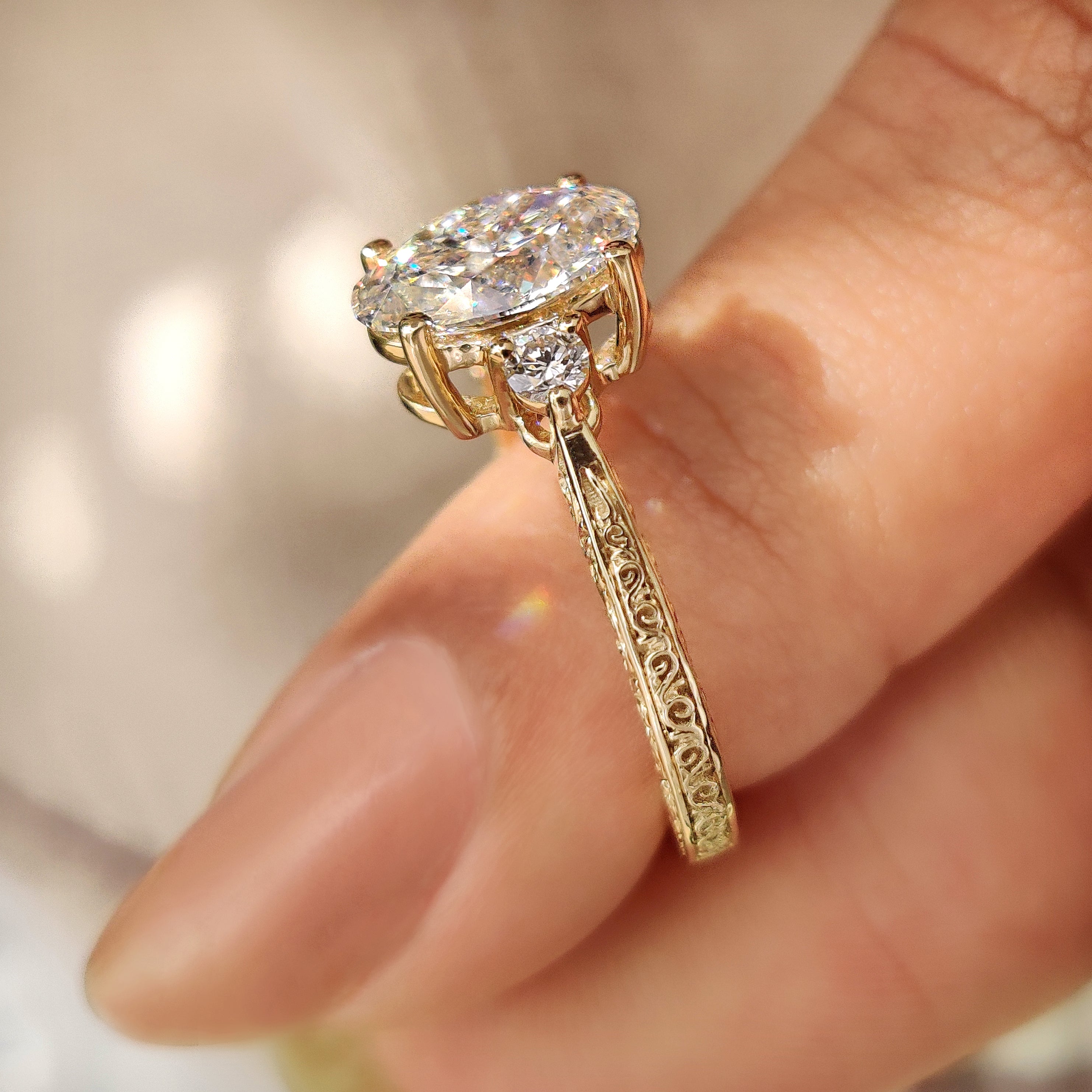 Four prong oval diamond ring with round side stones.
