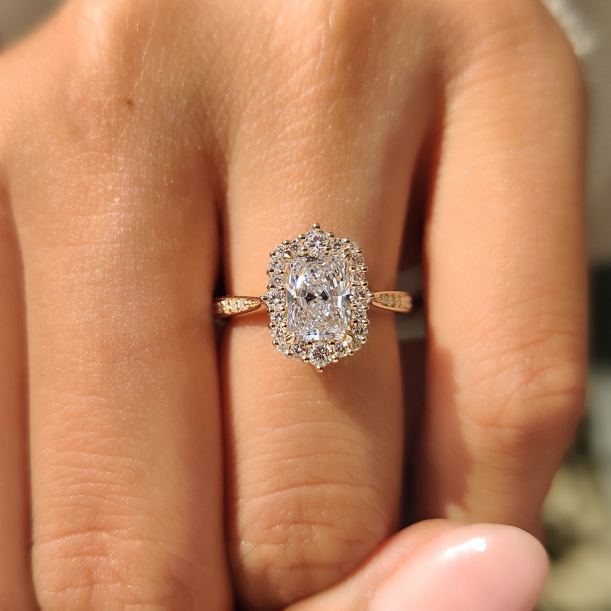 Radiant diamond ring with round diamond halo setting.
