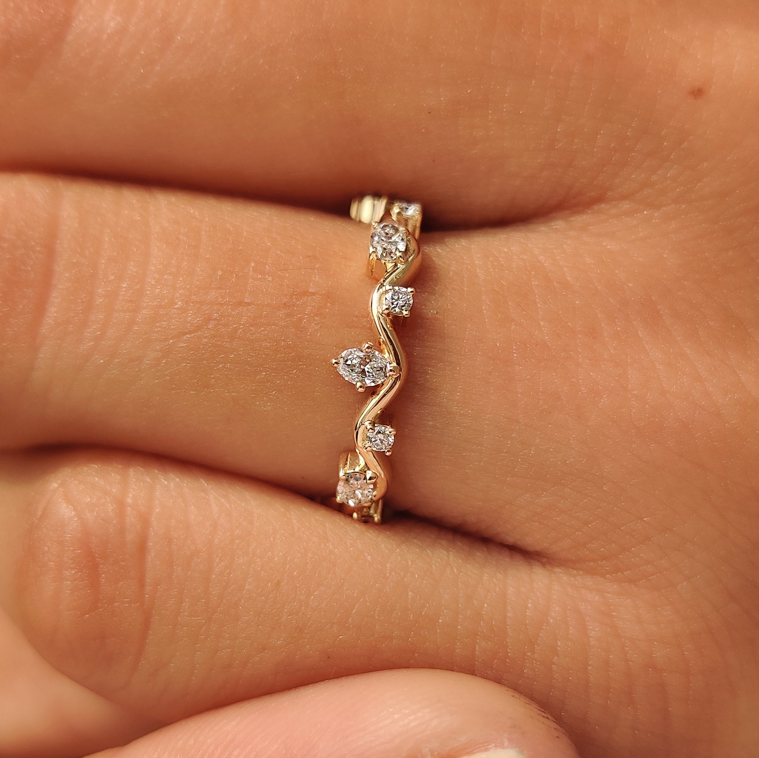 Round diamonds set between oval diamonds on a wave band.
