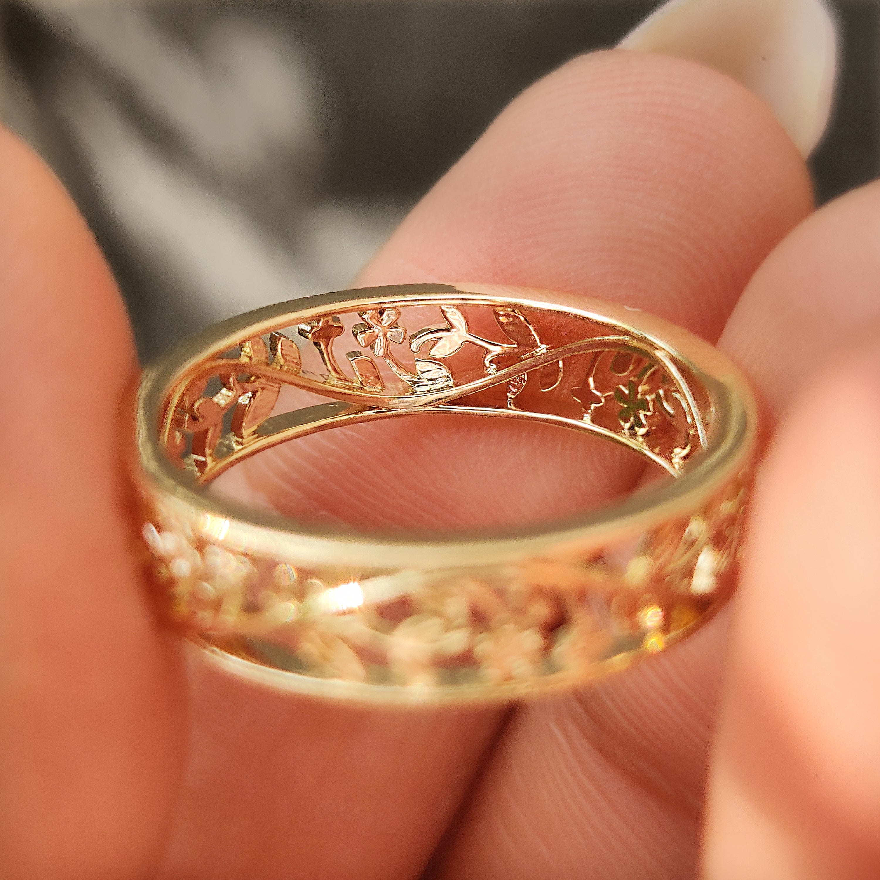 Side view of an openwork wedding band with floral metalwork.
