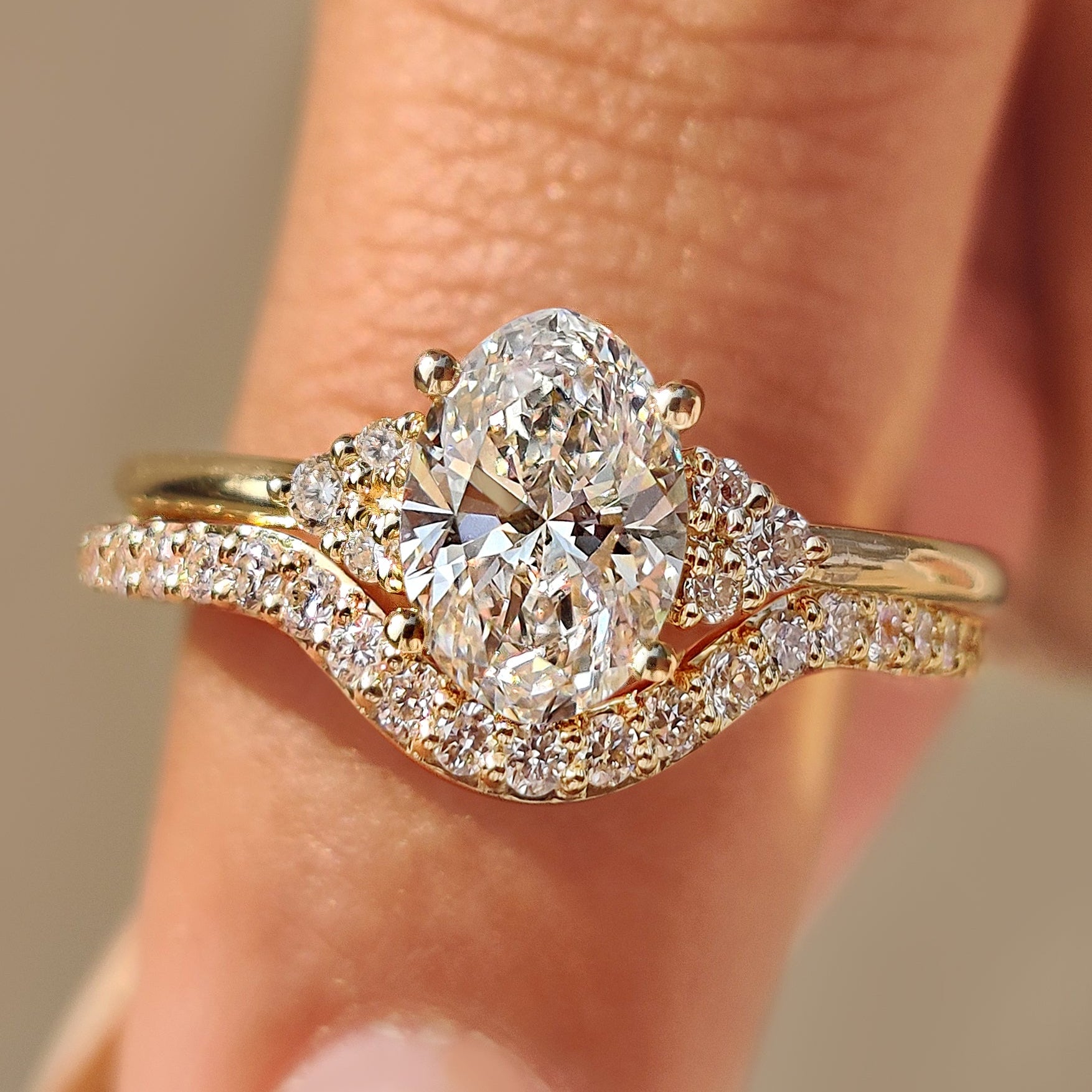Oval engagement ring set with curved diamond wedding band.
