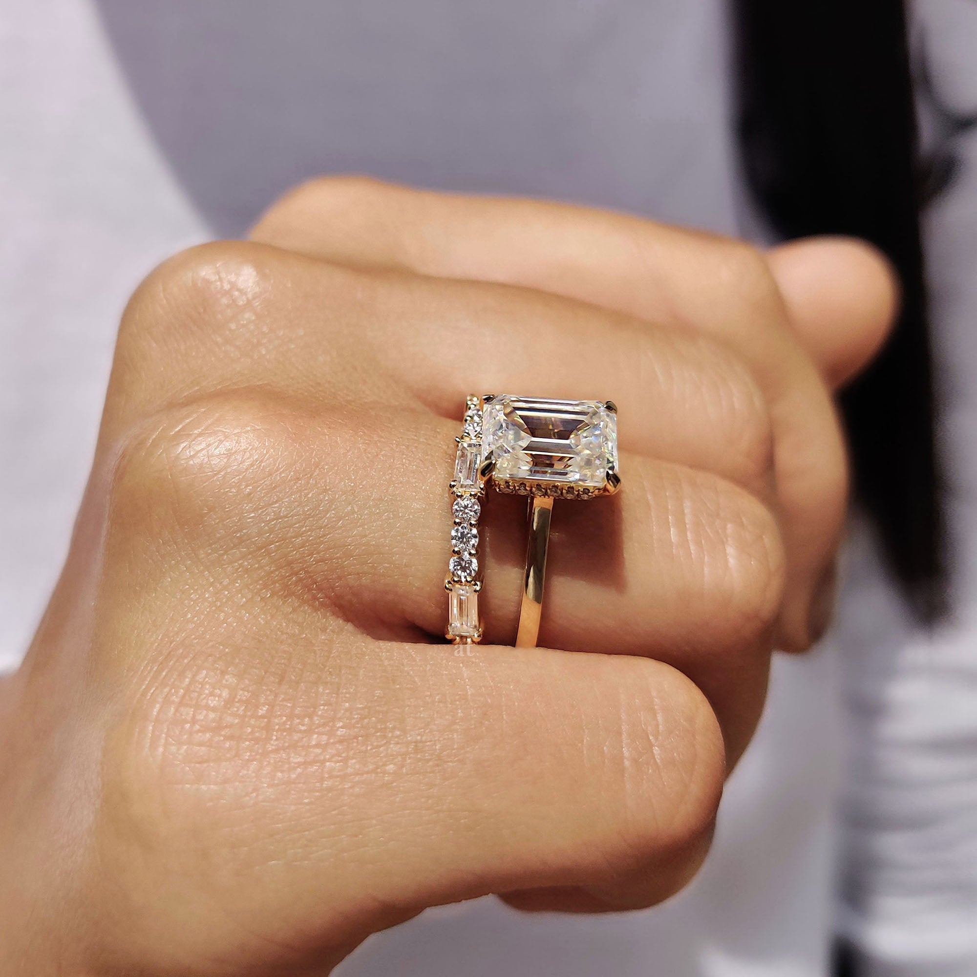 Emerald cut engagement ring with hidden halo and prong setting details.
