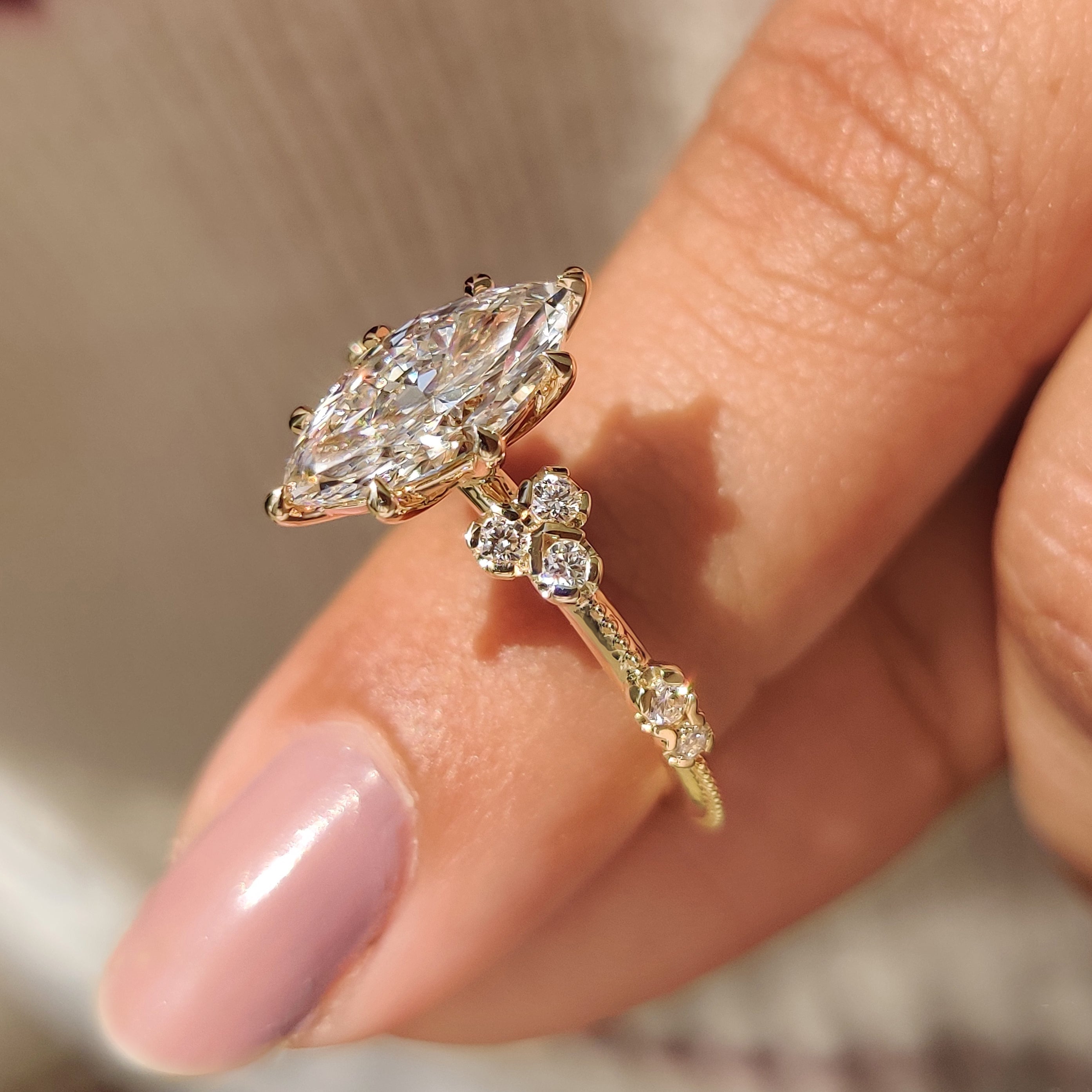Marquise diamond ring with eight claw prong setting and side stones.
