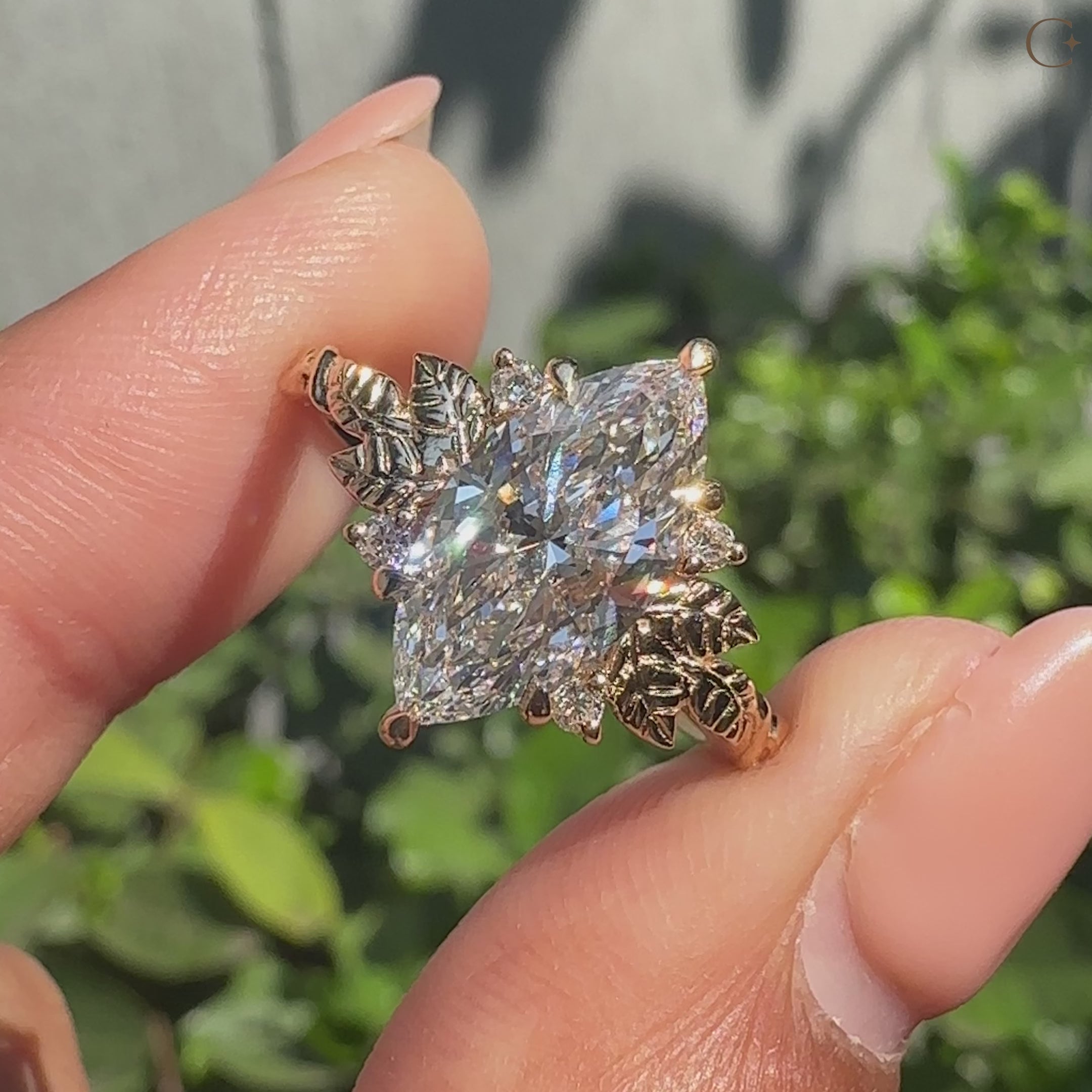 Marquise diamond ring with leaf shank and round side stones.
