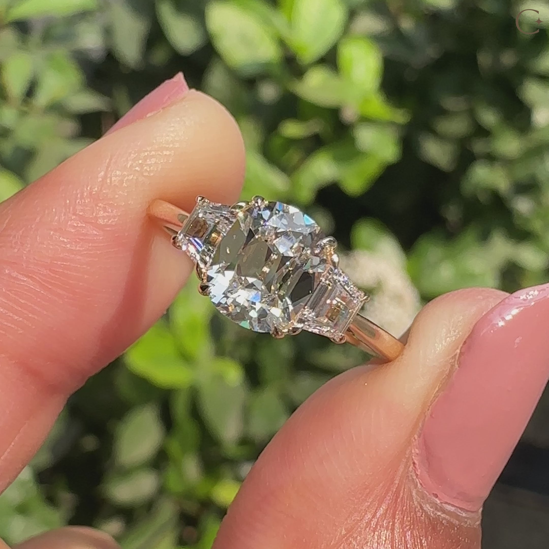 Three stone cushion cut diamond ring with trapezoid side stones

