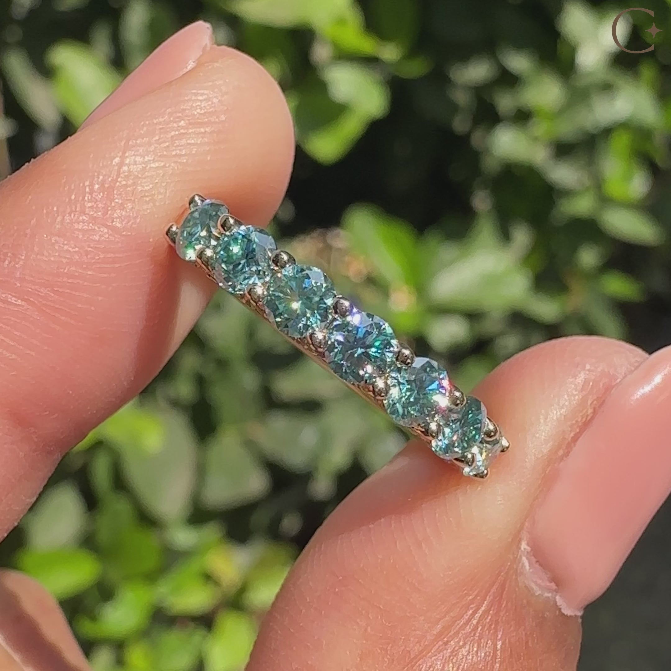 Blue round moissanite half eternity band with shared prongs.
