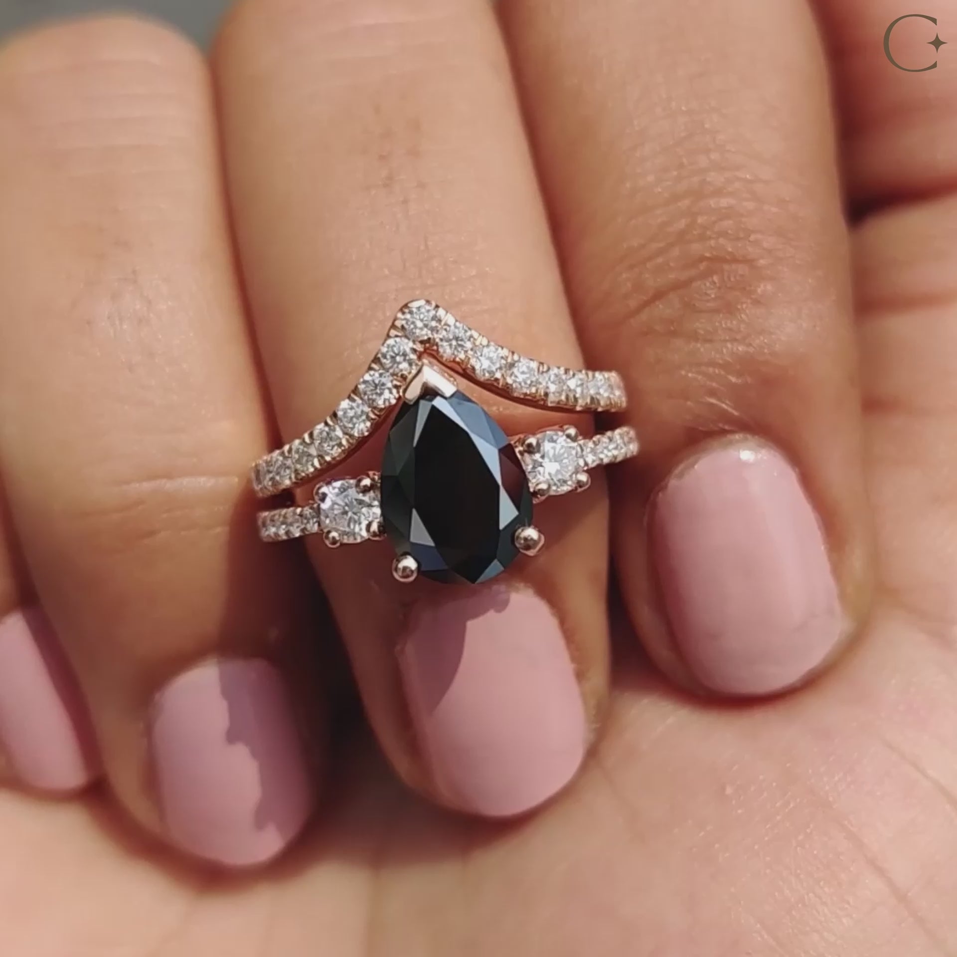 Pear cut engagement ring with black Moissanite and round side stones.
