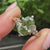 Floral engraved band on green oval engagement ring
