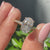 Hidden halo oval engagement ring with four claw prong and pave diamond band.
