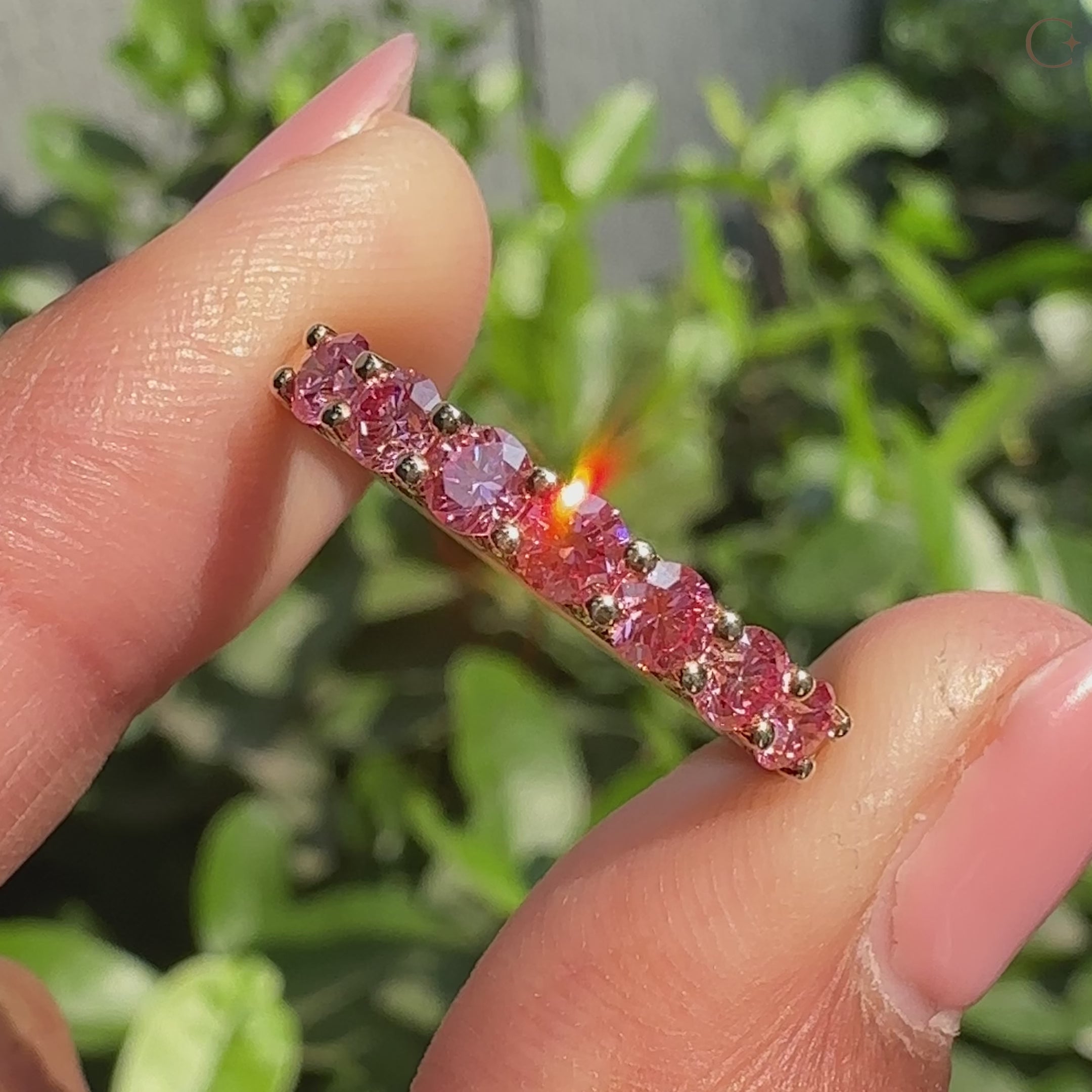 Pink diamond wedding band with shared prong setting.

