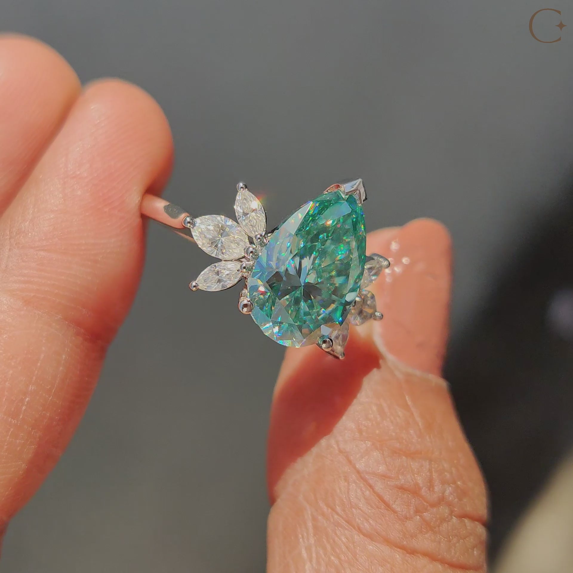 Seven stone engagement ring featuring pear cut cyan blue Moissanite and marquise side stones.