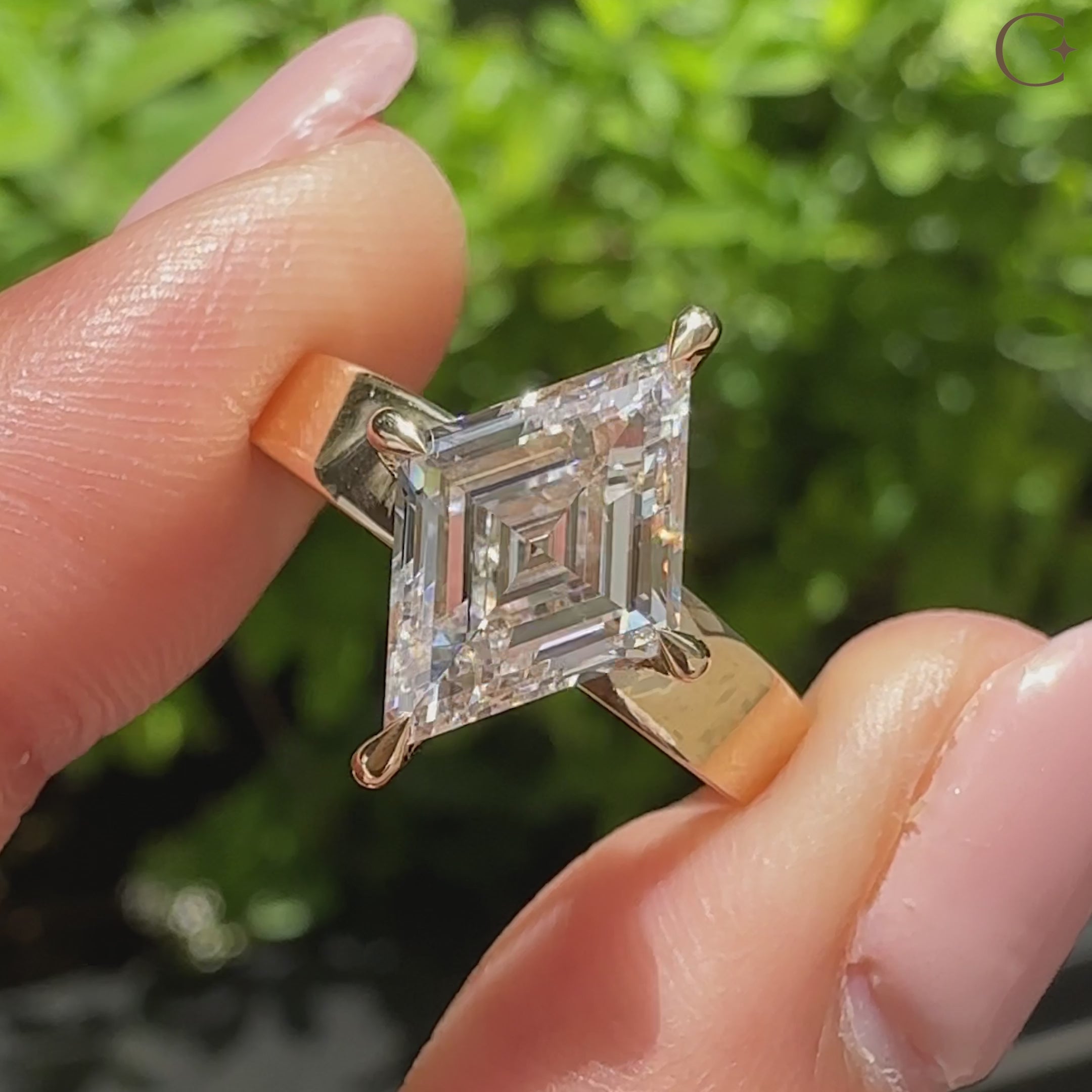 Solitaire lozenge diamond ring with four compass claw prongs
