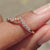 Tiara wedding band designed with a pointed curve and prong set moissanite stones.