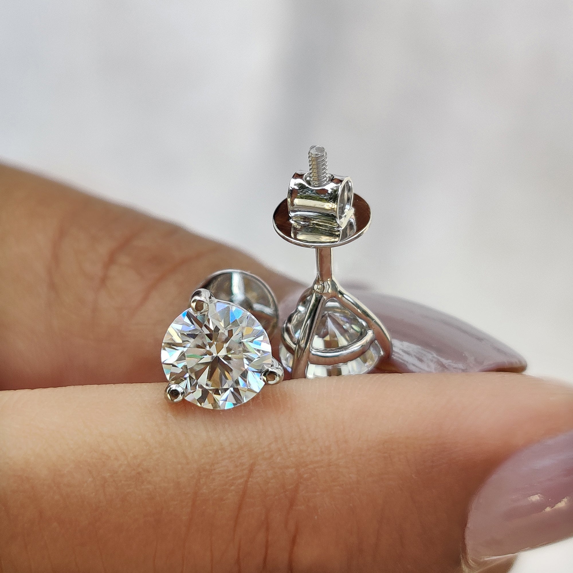 White gold earrings with martini style stud earrings using round cut Moissanite.
